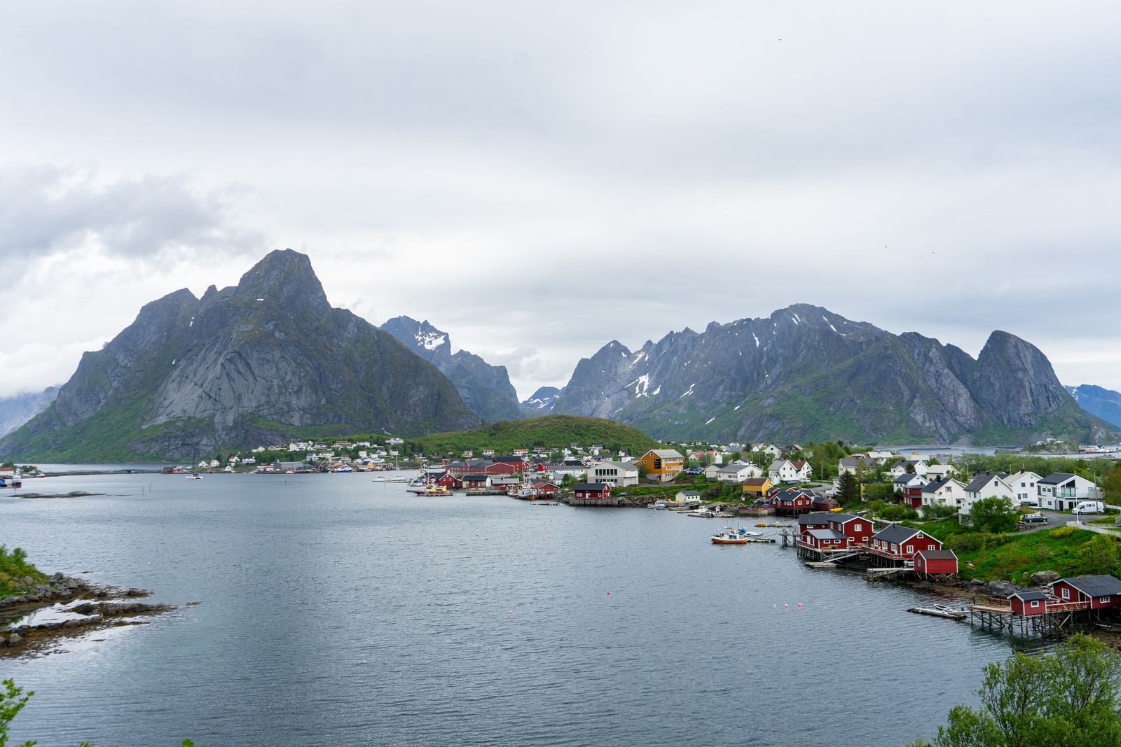 Red fishing cabins along the water at Reine in the Lofoten Islands, beneath jagged mountains